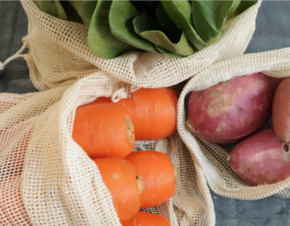 Carrots, potatoes, and leafy greens stored in organic cotton produce bags as a zero-waste alternative to plastic