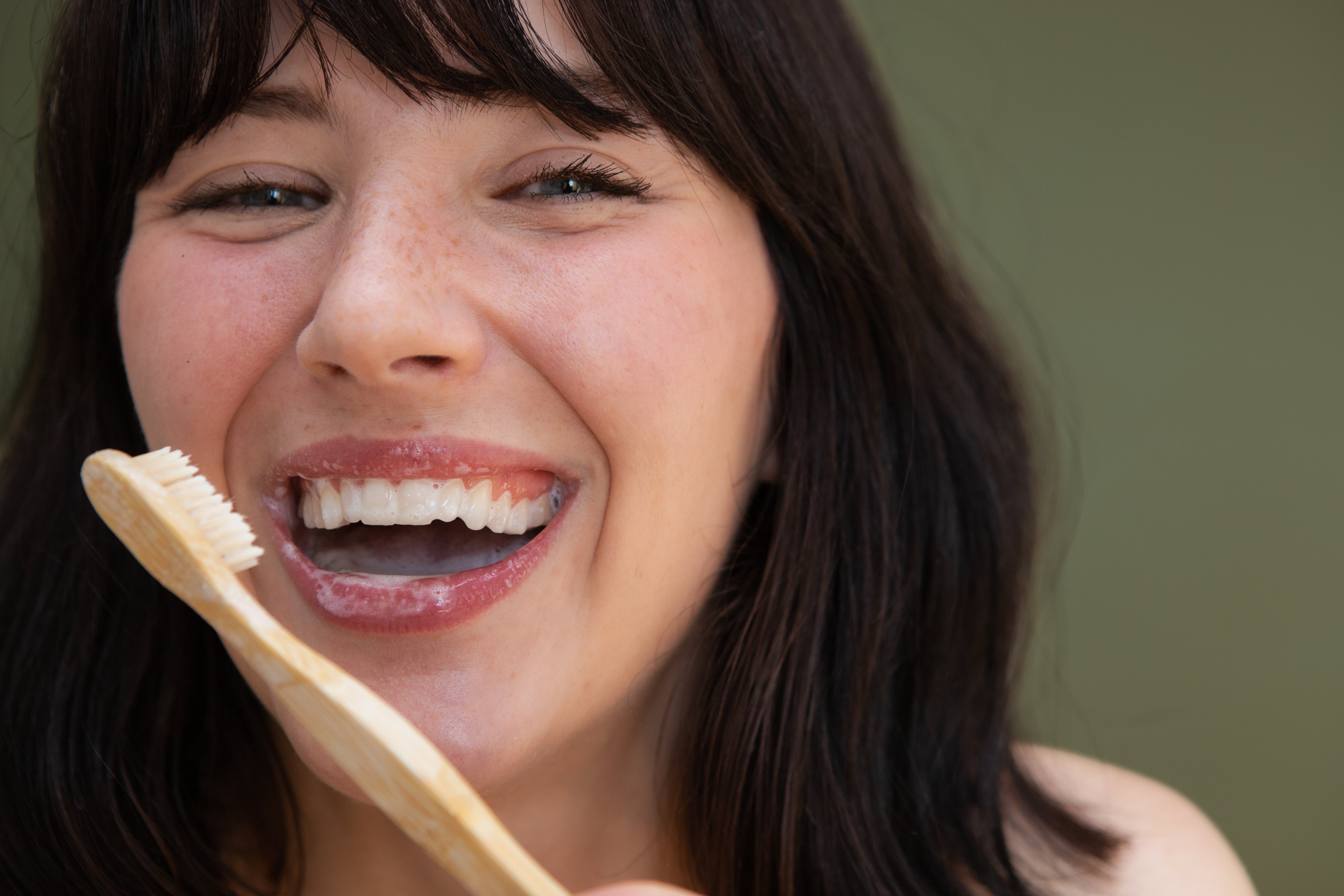 Smiling woman using bamboo toothbrush for sustainable dental care – plastic free oral care essentials in Canada