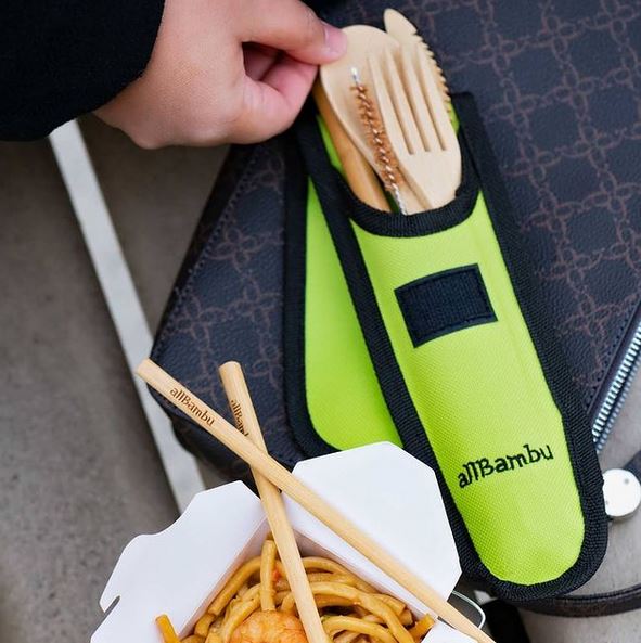 Close-up of bamboo utensils with smooth finish and engraved logo, showcasing detailed craftsmanship on the cutlery set.