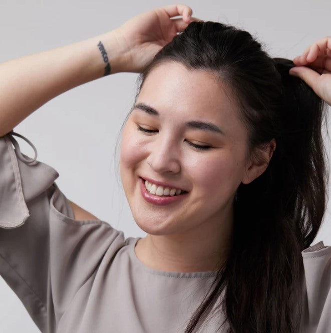 Close-up of the lip & cheek tint tube showing textured matte finish and botanical ingredient label detail.