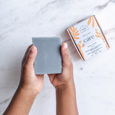 Close-up of the Blood Orange soap bar's textured surface with visible citrus oil specks and embossed logo detail
