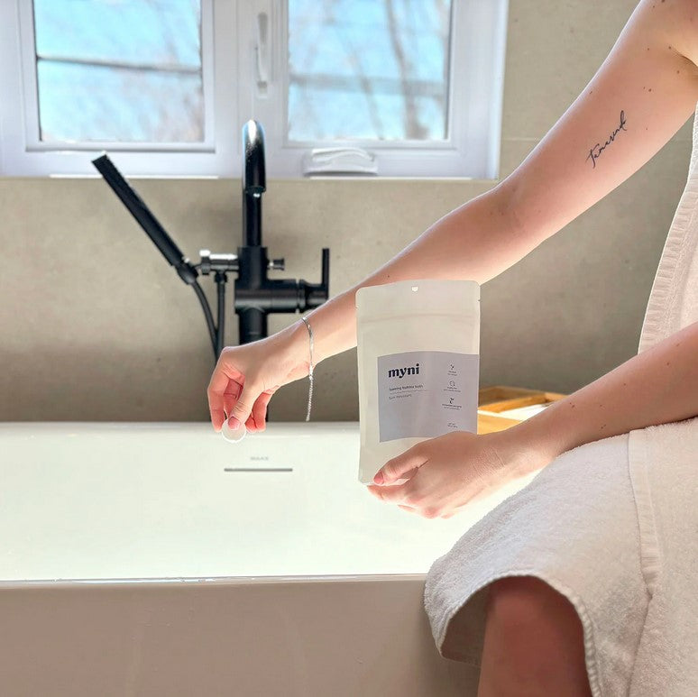 Close-up of Myni Bubble Bath Tablets packaging showing colorful label design and textured tablet surface for indulgent