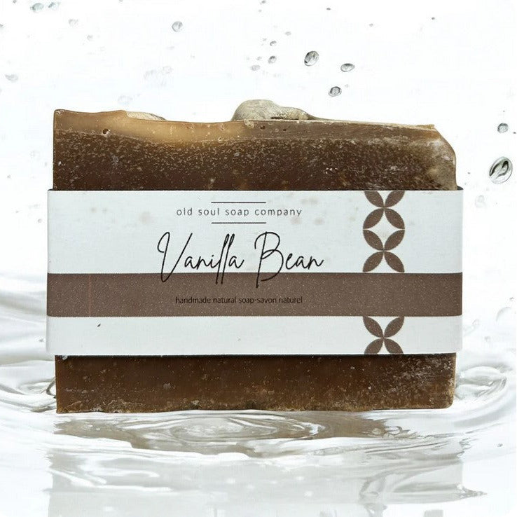 Close-up of three handcrafted vanilla soap bars wrapped in natural kraft paper with delicate twine accents, showcasing