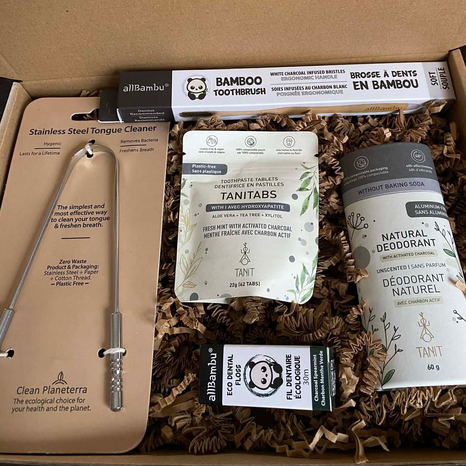 Charcoal Personal Care Kit featuring bamboo toothbrush, charcoal toothpaste tablets, eco dental floss, stainless steel tongue cleaner, and natural charcoal deodorant in a brown kraft gift box.