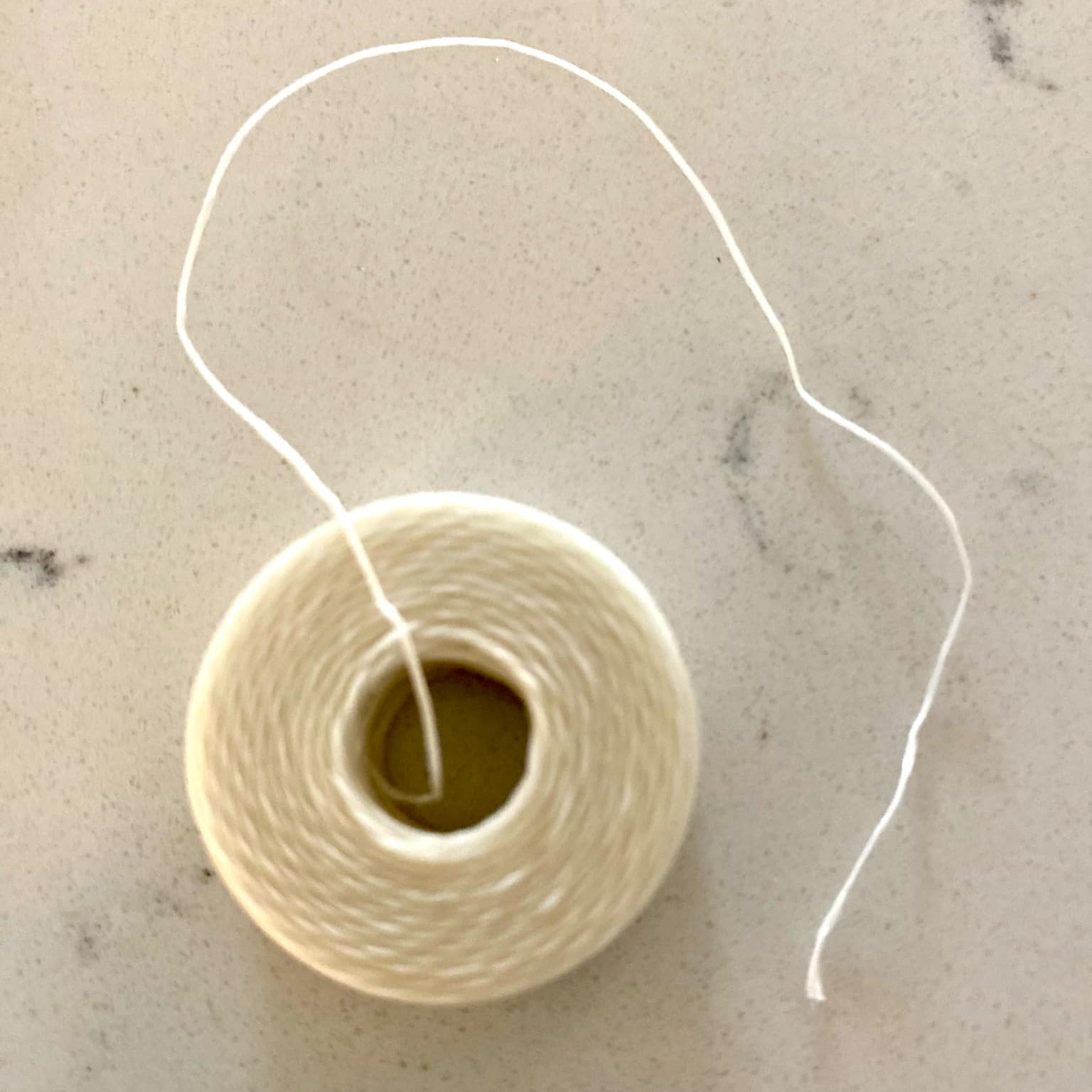 Close-up of biodegradable dental floss spool revealing mint-scented, textured floss with reforested packaging design