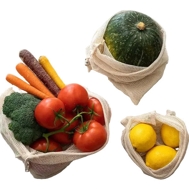 Mesh bags filled with vegetables and fruits on a white background