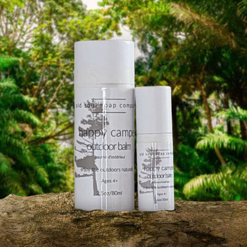 Close-up of the Happy Camper Outdoor Balm tube highlighting the textured, eco-friendly label with leaf illustrations and