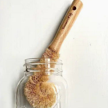 Close-up of the compostable bottle brush's textured bristles and eco-friendly wooden handle from an overhead angle