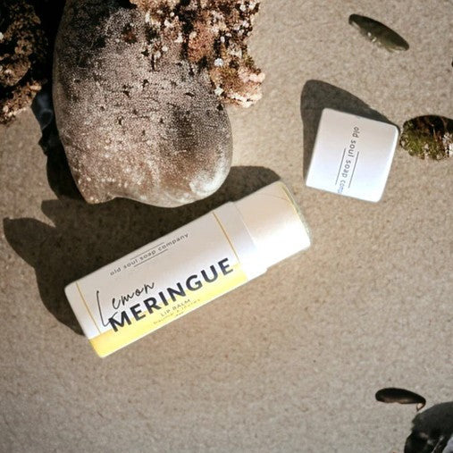 Close-up of Lemon Meringue Lip Balm tube displaying vibrant lemon and meringue swirl artwork on the label with textured