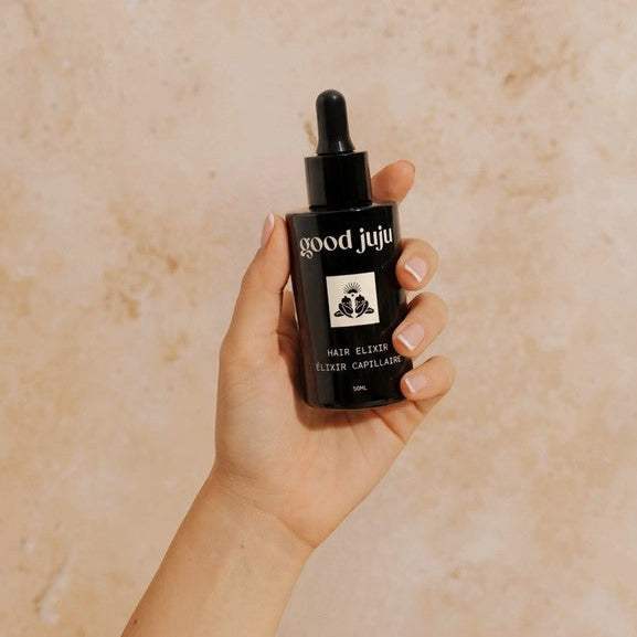 Good Juju Hair Elixir held in hand, lightweight nourishing scalp oil for healthy hair