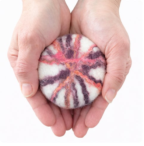 Felted Floral Sage Soap bar in a pair of hands featuring natural wool felted floral design in pinks, purple and orange on a white background handcrafted by Simply Natural Canada