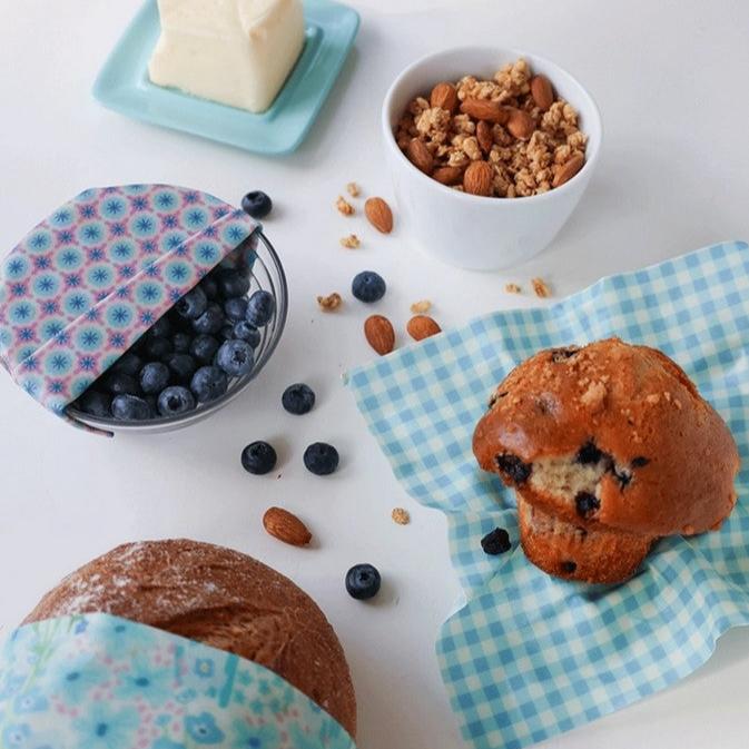 Close-up of folded beeswax wraps displaying natural fabric patterns and textured beeswax coating for reusable food storage.