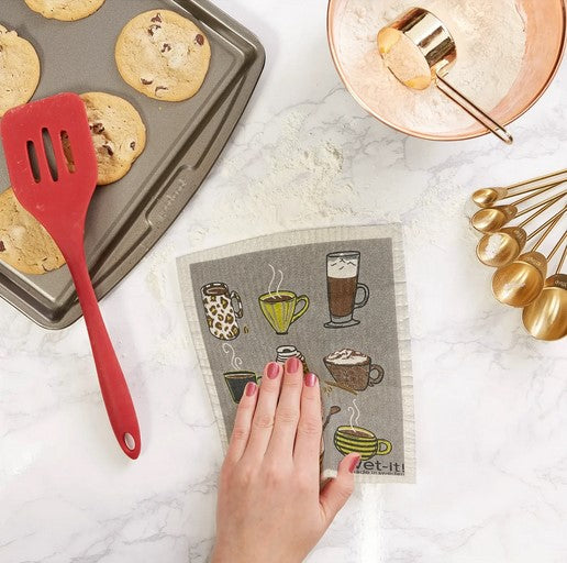 hand using coffee shop Wet-It Swedish dishcloth on kitchen counter baking scene cookies tray eco friendly reusable sponge cloth plastic free cleaning