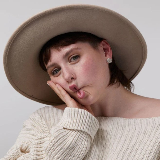 Close-up of the lip and cheek tint tube's textured matte cap with visible product shade swatch on skin, highlighting natural