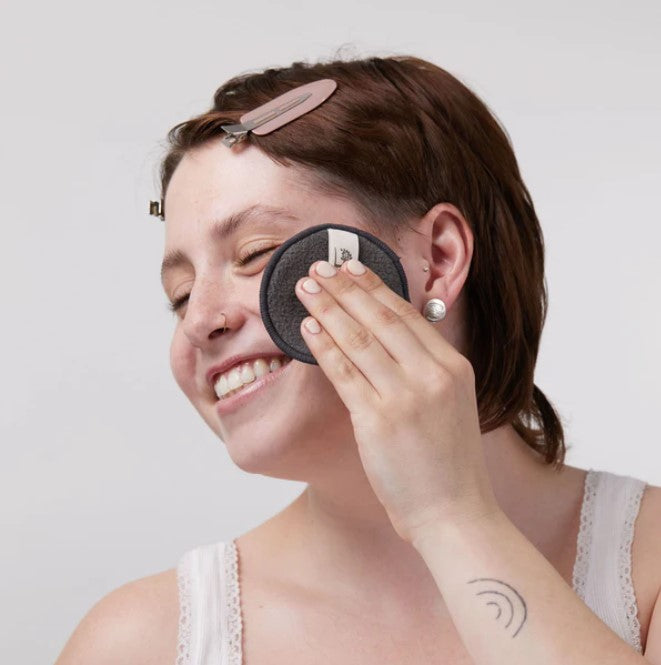 Close-up of bamboo charcoal-infused reusable facial rounds stacked, highlighting soft texture and eco-friendly branding on