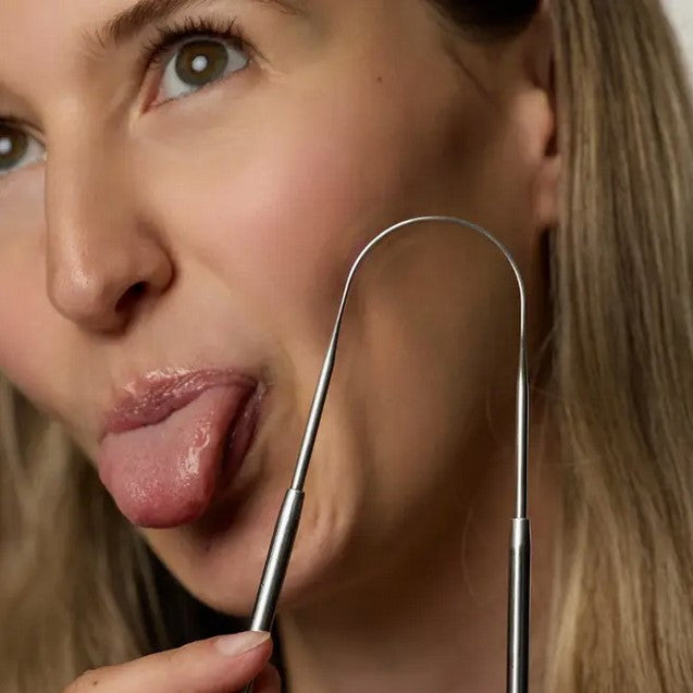 Close-up of mint-colored rubber textured tongue scraper with beveled edge and engraved branding detail from an overhead