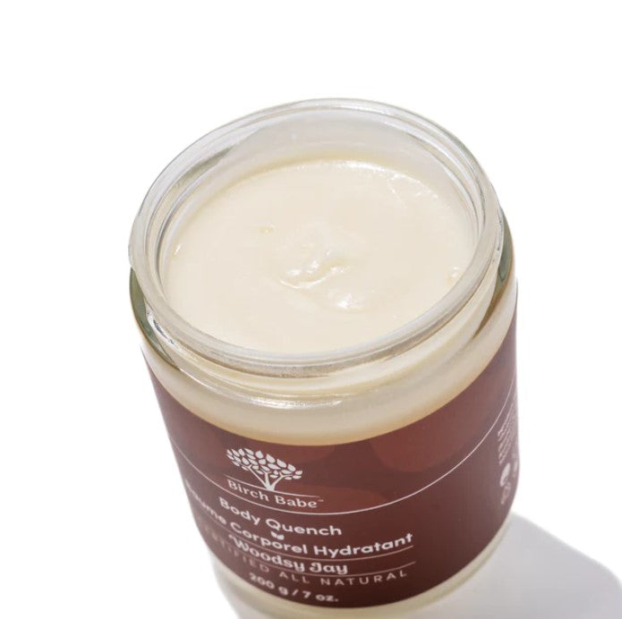 Close-up of the Body Quench - Woodsy Jay lotion bottle showing textured label and amber-colored cap, highlighting packaging