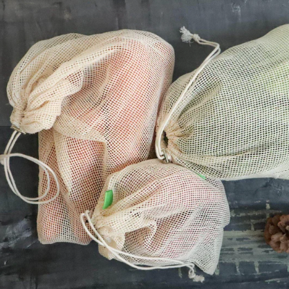 Close-up of multi-sized organic cotton produce bags with drawstring closures and breathable mesh details for fresh
