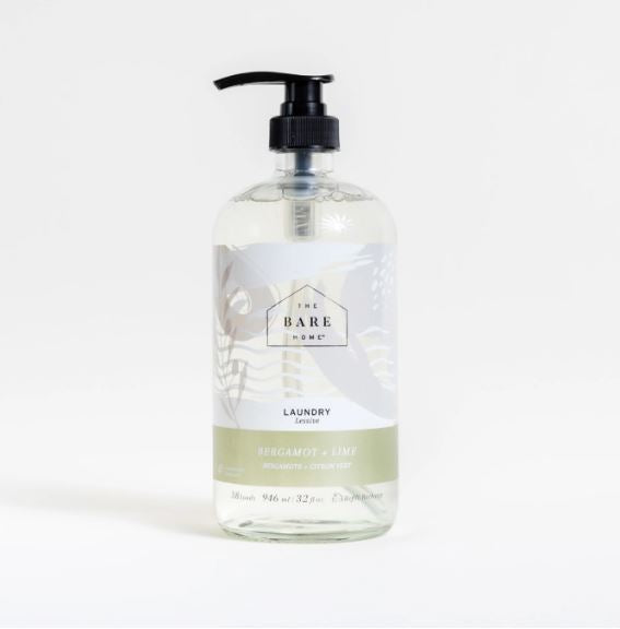Close-up of clear liquid detergent being poured from the Bergamot Lime bottle with visible fragrance notes on the label