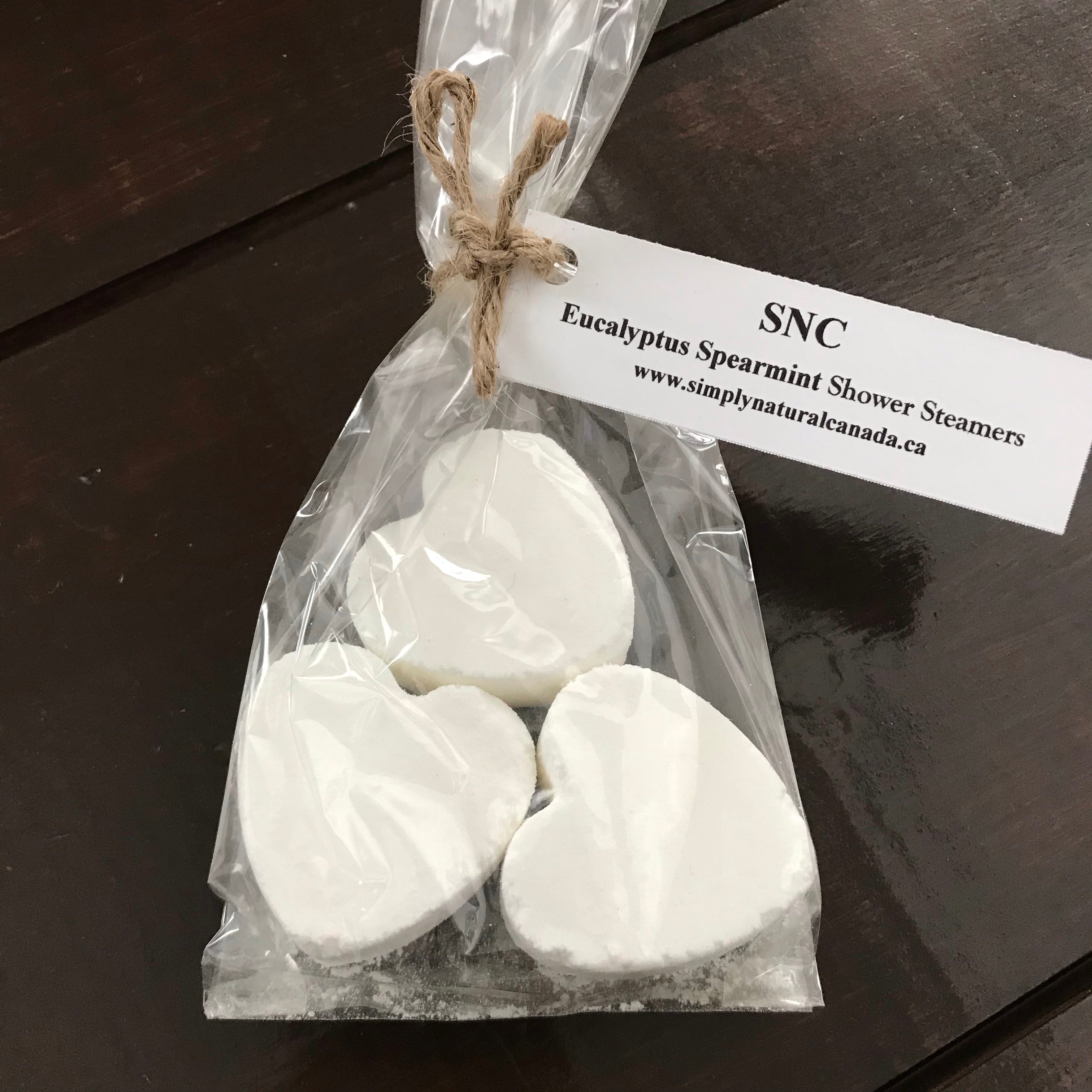 Close-up of textured peach-colored shower steamer hearts with visible natural ingredients and subtle floral accents for