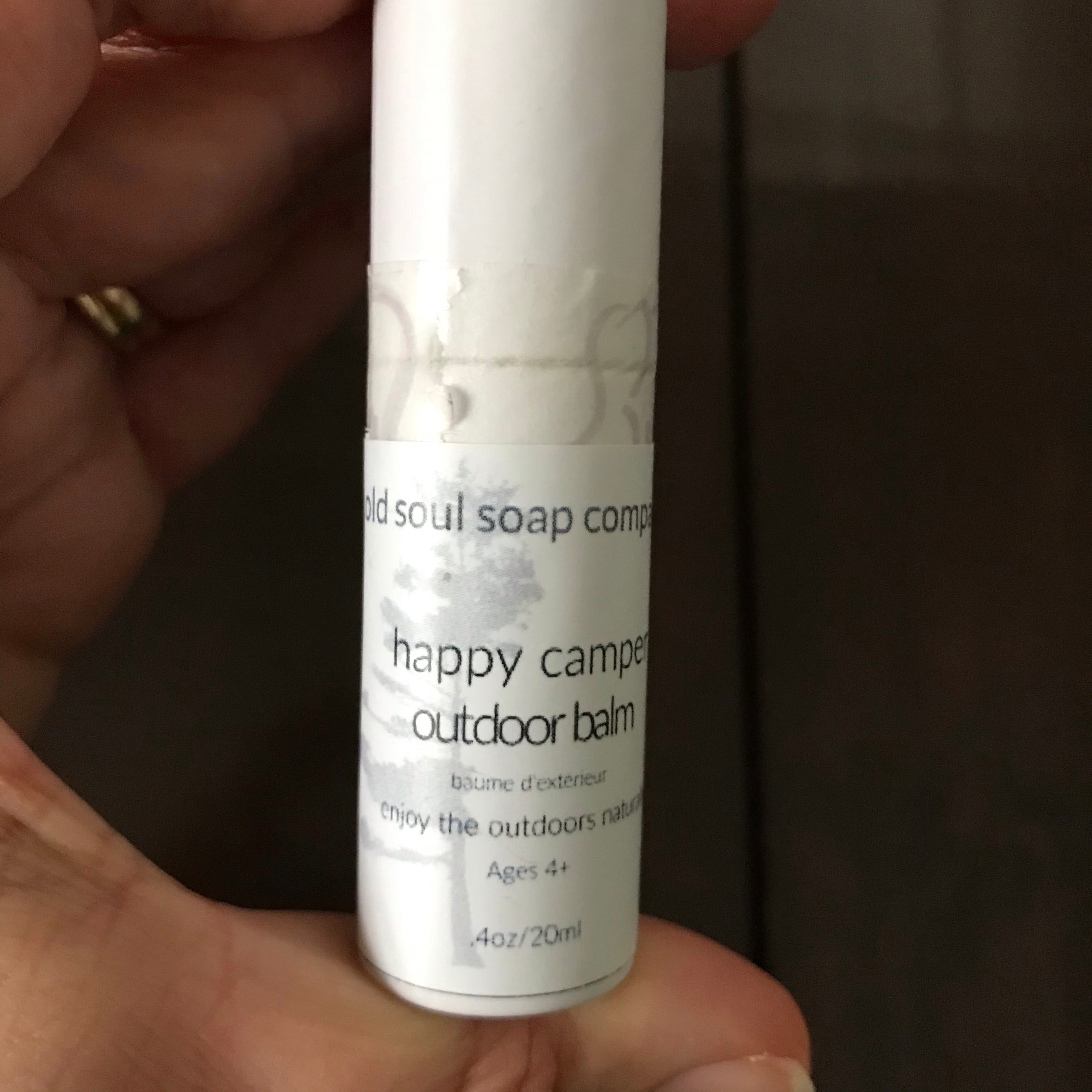 Close-up of Happy Camper Outdoor Balm jar cap showing textured grip and embossed logo detailing