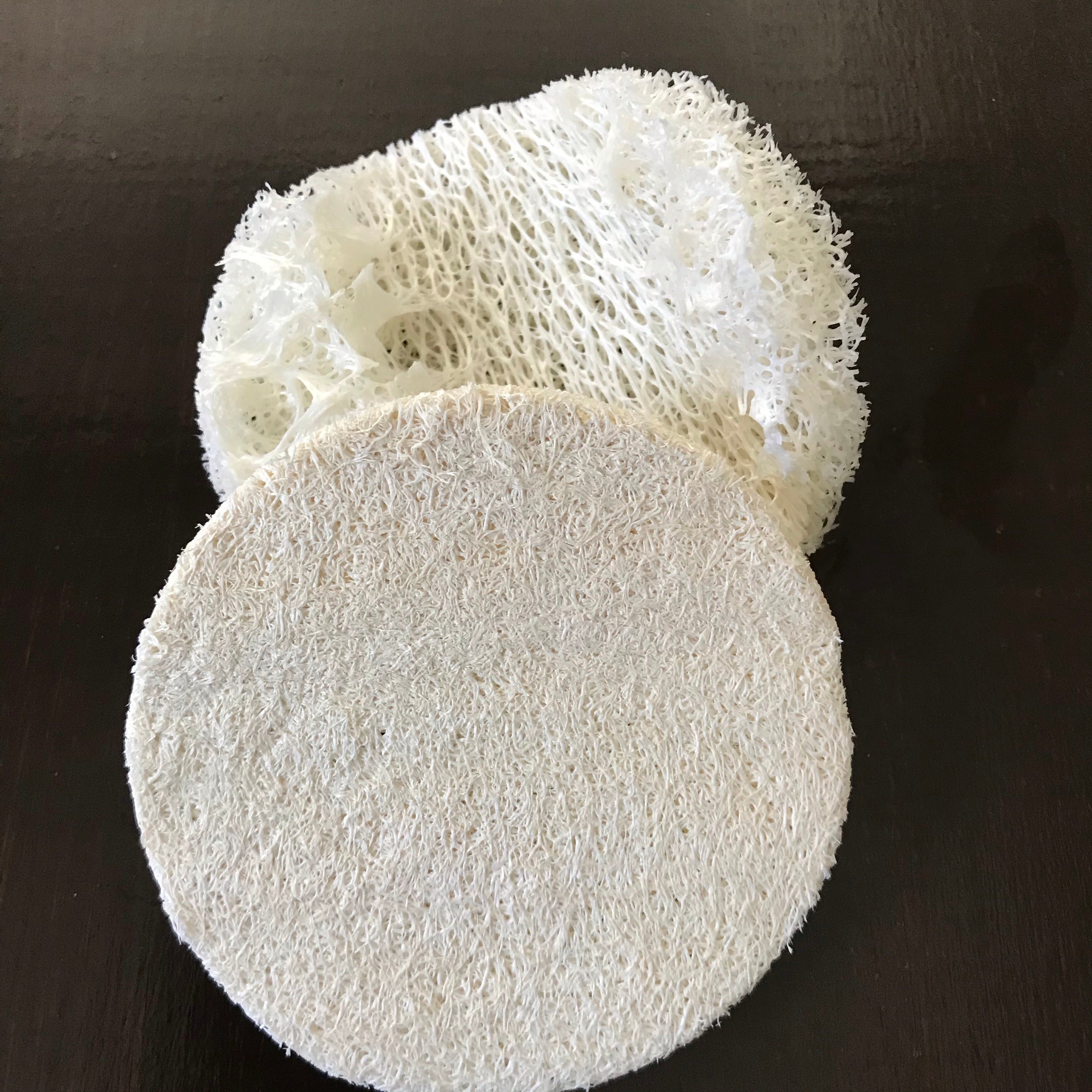 Close-up of textured surface showing natural fibers and porous detail of the round loofah sponge from an overhead angle.
