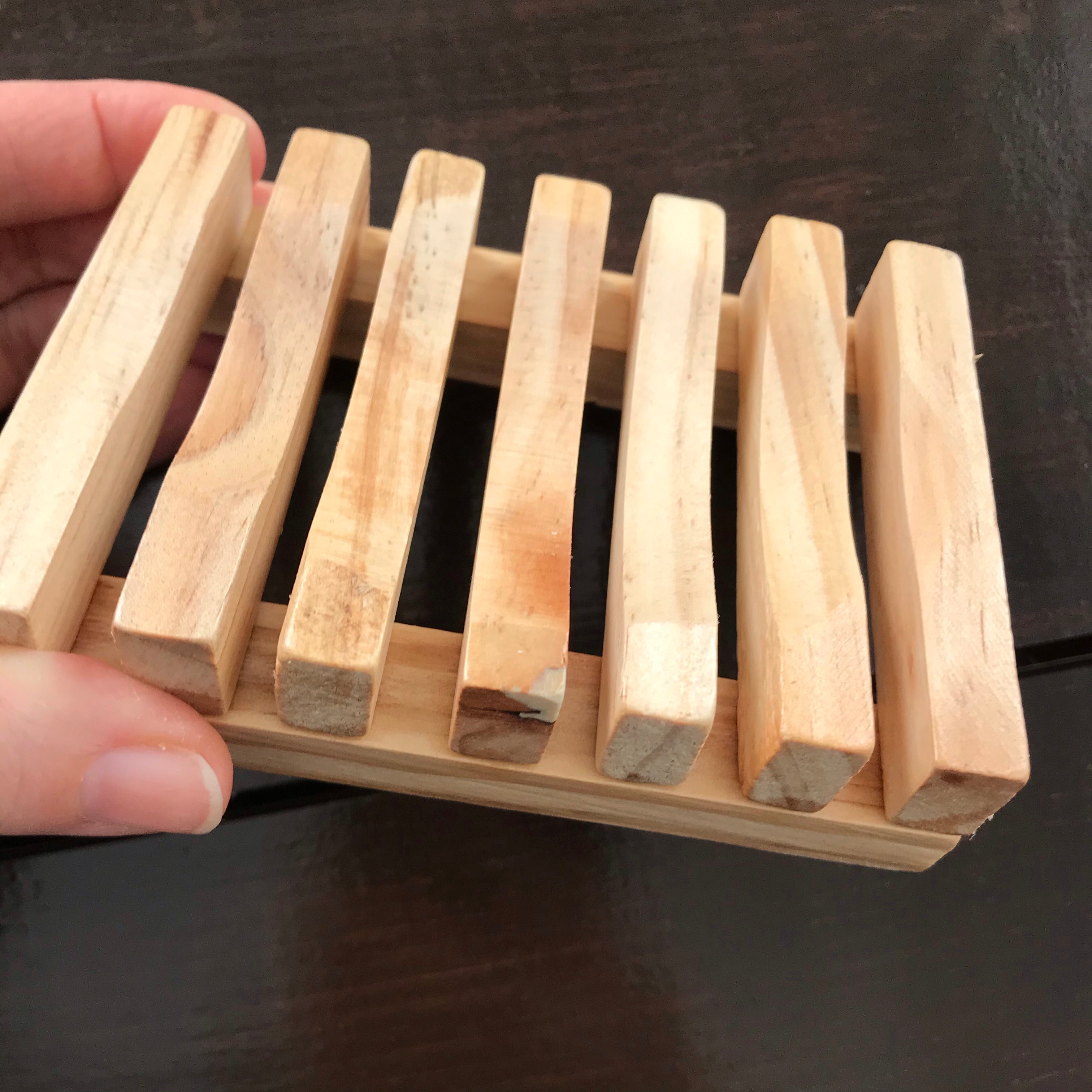 Close-up of the slatted wooden soap dish showing textured grain and rounded edges from a front-angle perspective