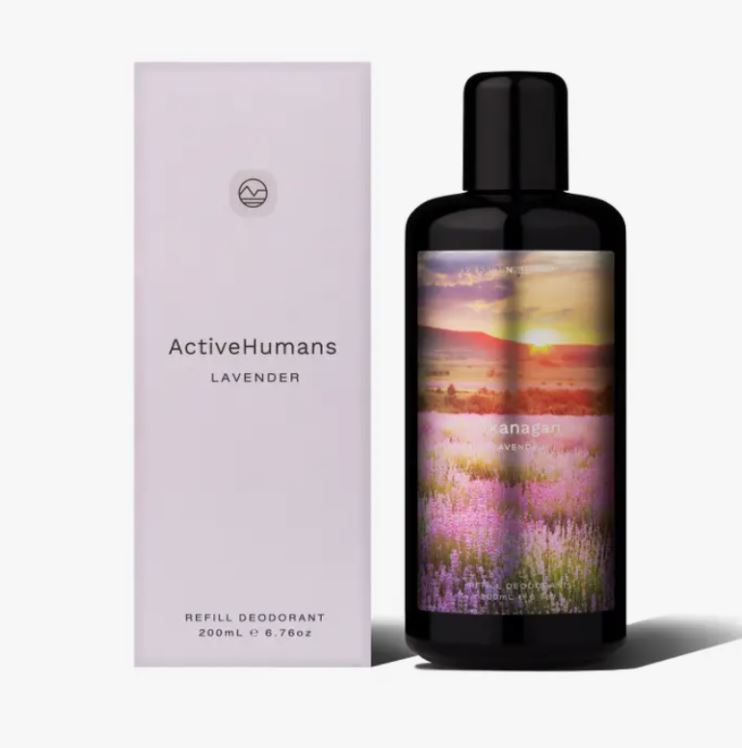 Close-up of lavender-scented spray nozzle with clear glass bottle and textured white label featuring green accents