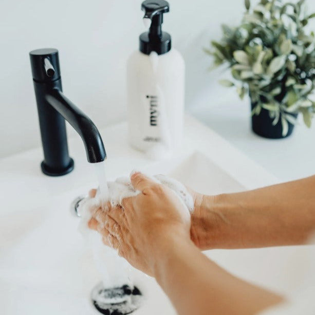 Close-up of Myni Clean Hands Kit's textured liquid soap with natural ingredients and eco-friendly pump dispenser visible.