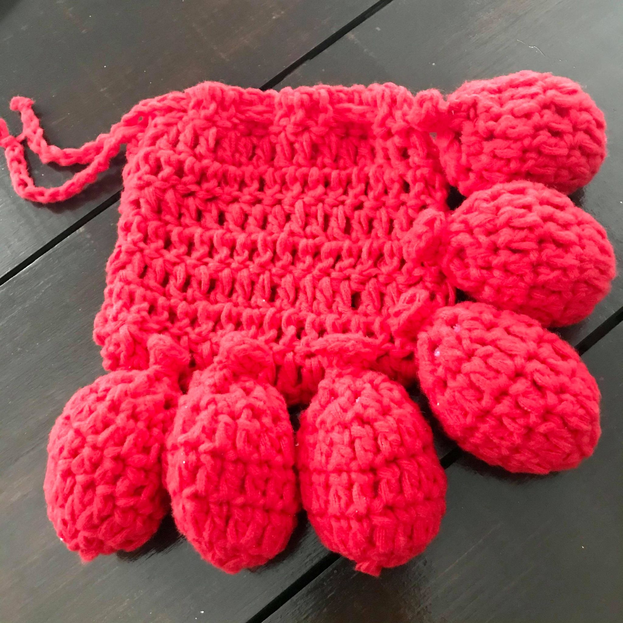 Close-up of hand-crocheted water balloons with textured, colorful yarn and small, tightly stitched openings for filling