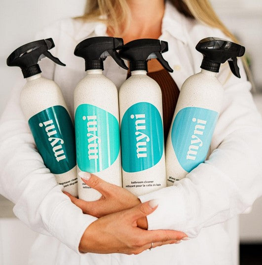 Woman with reusable wheat straw spray bottles with MYNI cleaning tablet solutions for low-waste household cleaning