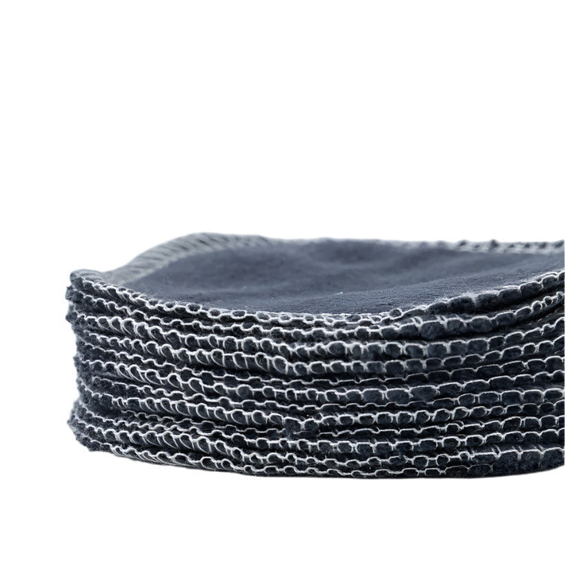 Close-up of charcoal-infused reusable facial rounds stacked, showcasing textured surface and soft cotton material with