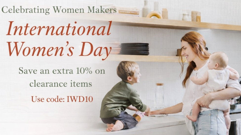 Woman holding a baby and a child in a kitchen, celebrating International Women's Day with promotional text.