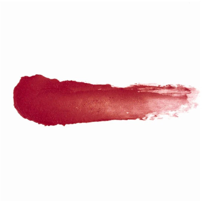 Close-up of Ruby Rebel Lip & Cheek Tint tube showing the matte texture and vibrant red shade against a neutral background.