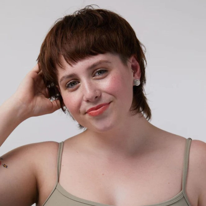 Close-up of the Sunset Seeker Lip and Cheek Tint tube displaying natural coral shade and matte finish label detail.