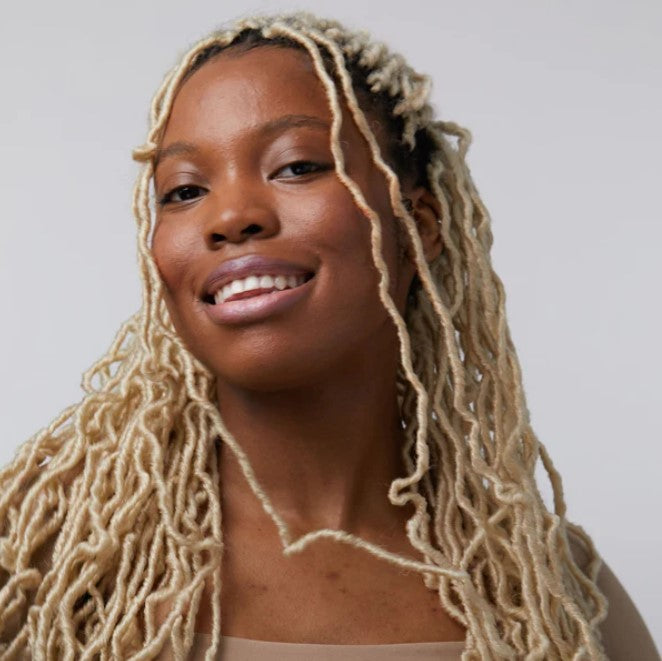 Close-up of the creamy matte formula swatched on skin, highlighting buildable texture and natural tint with a subtle floral