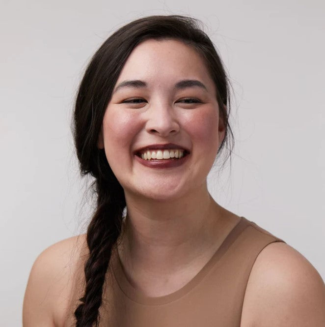 Close-up of the creamy, matte Deep Burgundy Lip & Cheek Tint applied with a finger, highlighting its smooth texture and