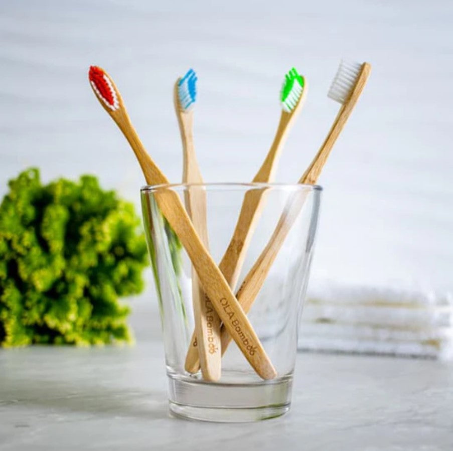 Close-up of four gently rounded bamboo toothbrushes showcasing textured bamboo handles and soft nylon bristles arranged in a