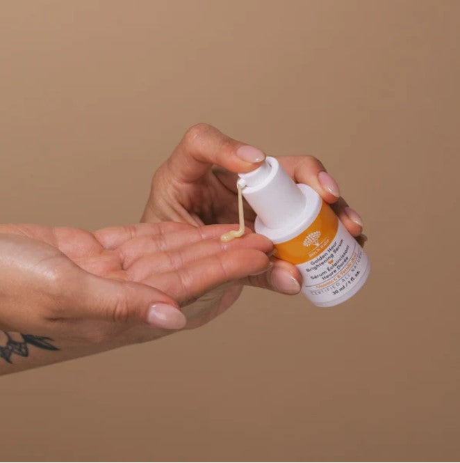 Close-up of the Golden Hour Brightening Serum’s sleek glass bottle with a white pump dispenser, highlighting the