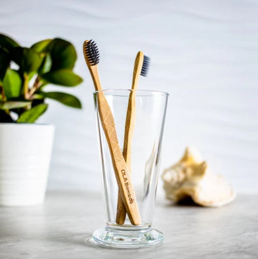 Close-up of two Canadian-made charcoal bamboo toothbrushes displaying textured bristles and natural wood grain surfaces.