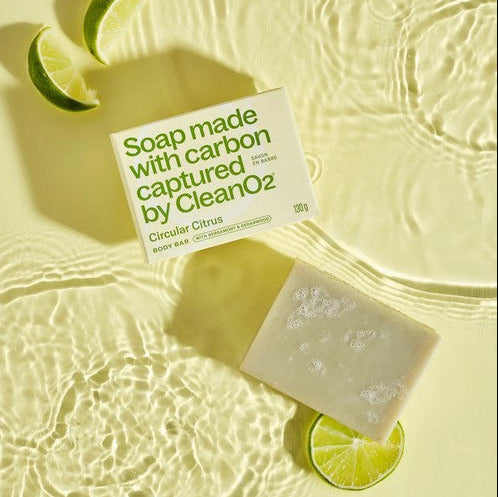 CleanO2 Circular Citrus Body Bar and packaging displayed with fresh lime slices on rippling water, showcasing carbon-capture soap with citrus and cedarwood scent.