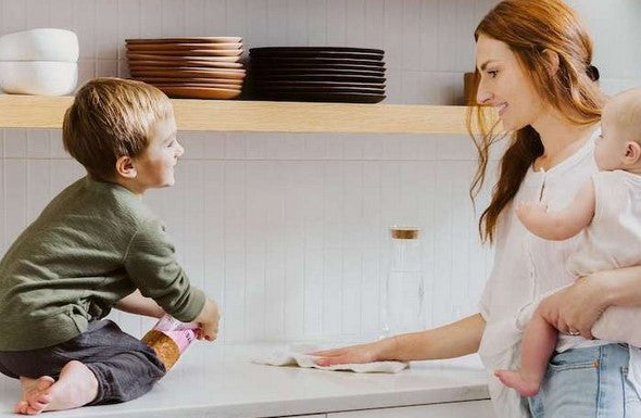 Mother cleaning kitchen counter with eco-friendly spray cleaner in modern sustainable home