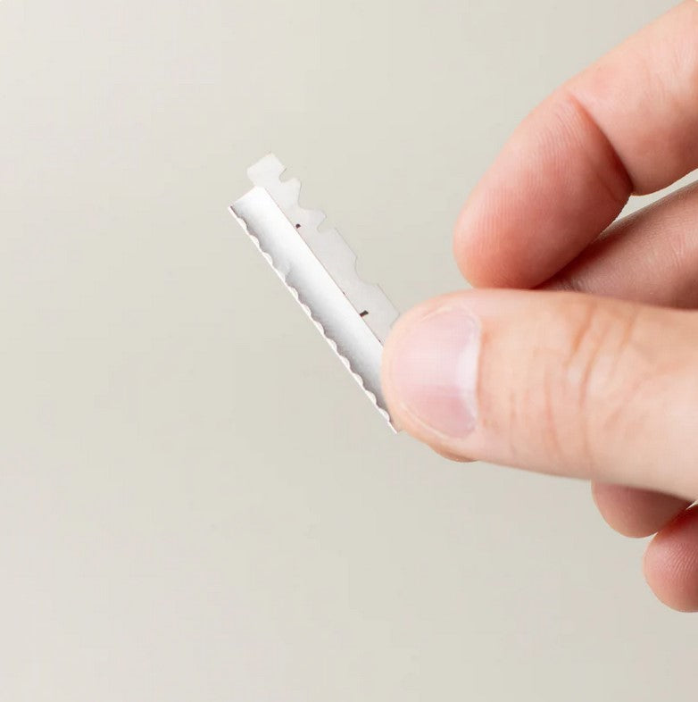 Close-up of dermaplaner refill blades with sharp, precisely aligned edges and protective coating detail from an overhead