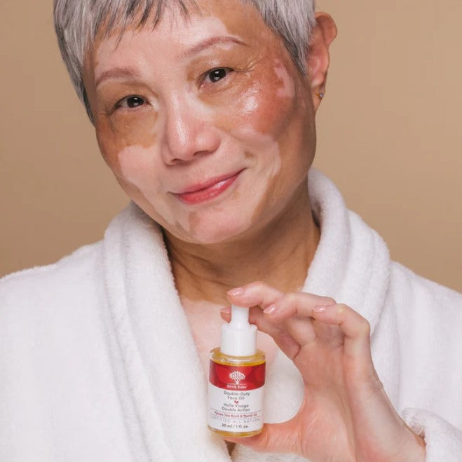 Close-up of the Double Duty Face Oil bottle highlighting the sleek dropper cap and textured label details on a neutral