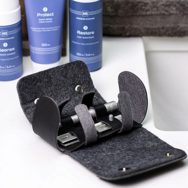 Henson Shaving Travel Case open on bathroom counter holding razor and blades beside Henson skincare products