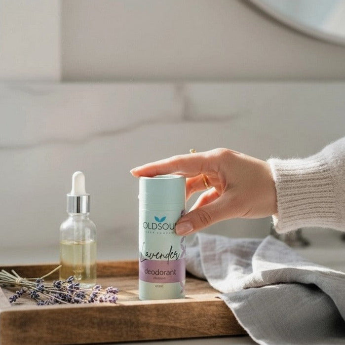 Hand reaching for Lavender Natural Deodorant by The Old Soul Soap Company, a Canadian-made aluminum-free deodorant in a compostable cardboard tube, styled with lavender and essential oils.