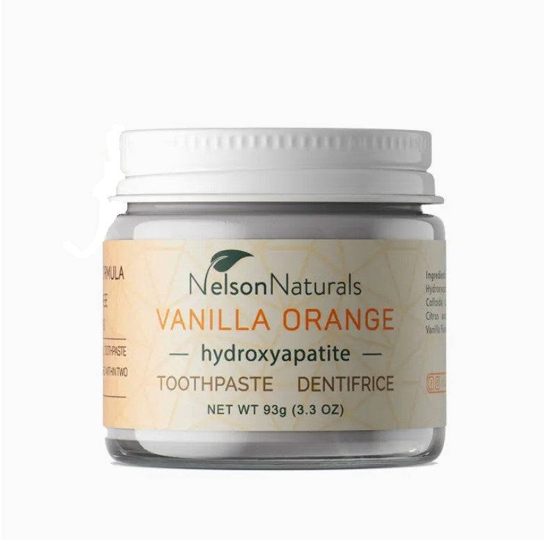Nelson Naturals Vanilla Orange toothpaste in a clear glass jar with white screw lid, textured surface, showing orange and