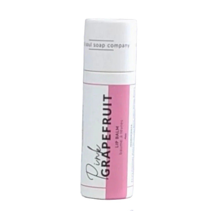 Close-up of the pink grapefruit-colored balm tube cap with textured finish and clear branding label in soft natural light on a white background