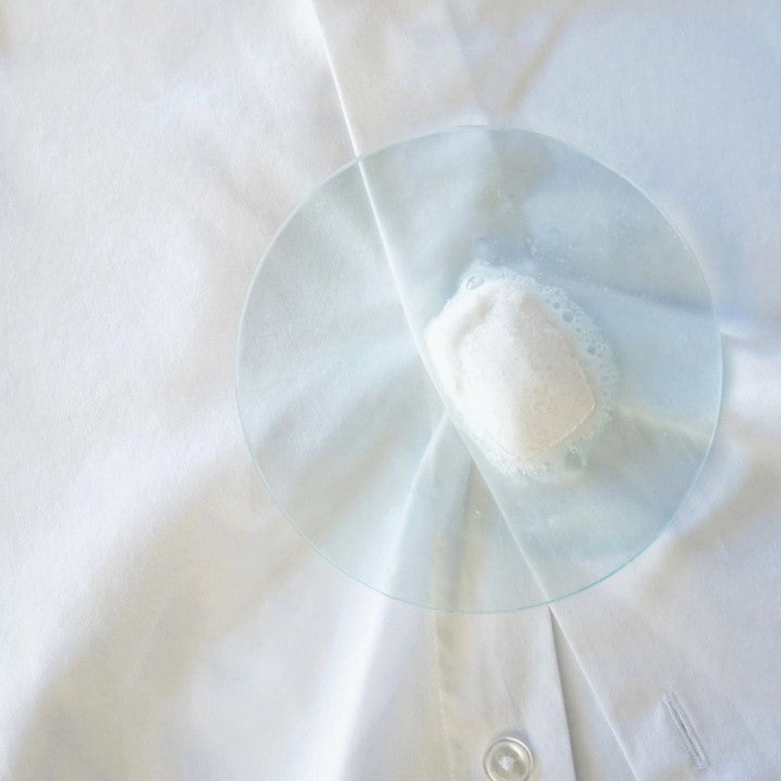 Plastic-free Tanit Laundry Detergent Tablet dissolving on white shirt to remove stains naturally