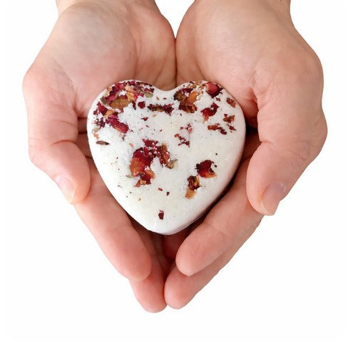 Simply Natural Canada rose geranium heart bath bomb with dried botanicals held in hands and on a white background